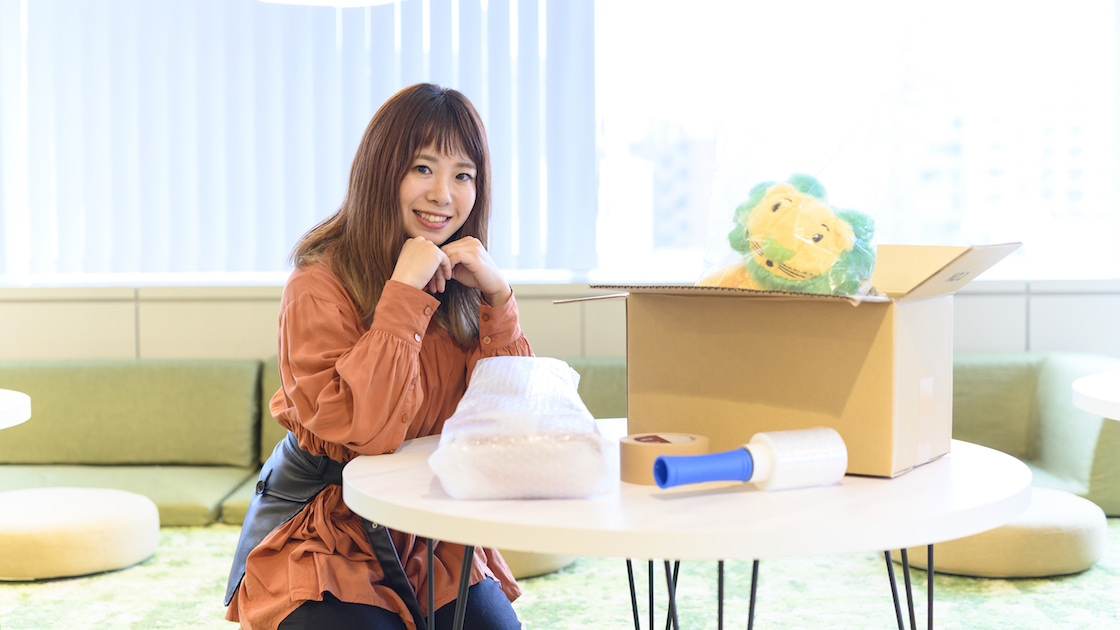 梱包資材の前に笑顔を浮かべる西田さん