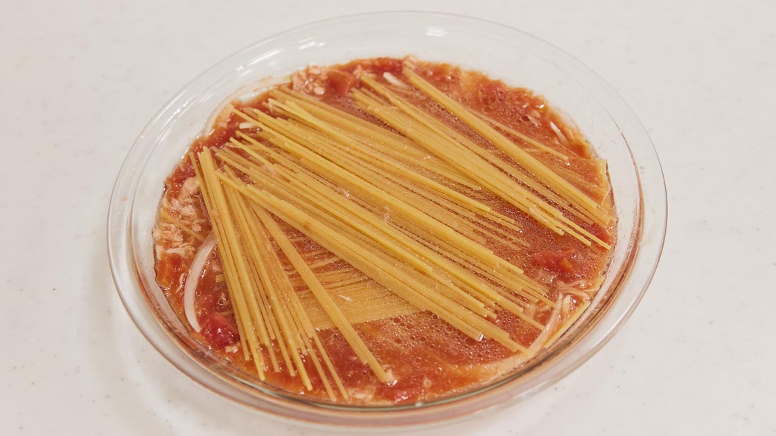 （2）耐熱皿（半分に折ったパスタが入る大きさで、深めのもの）にカットトマト、ツナ（油ごと）、玉ねぎ、Aを入れて混ぜ、スパゲティを半分に折って加え、なじませる。
