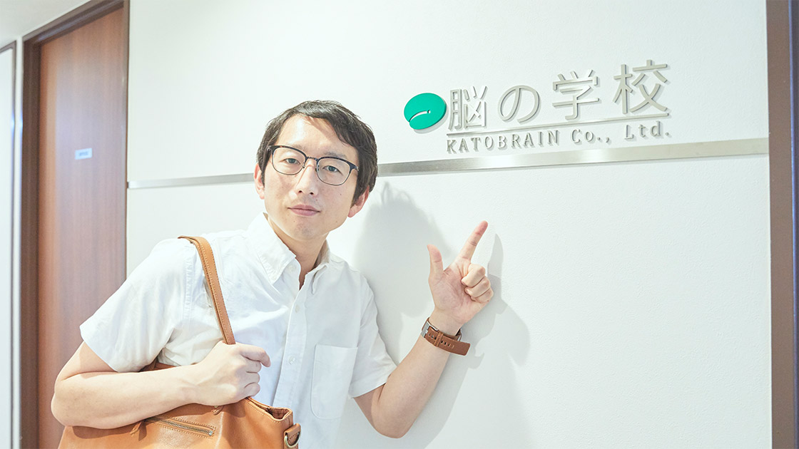 脳の学校の前に立つライター・斎藤充博